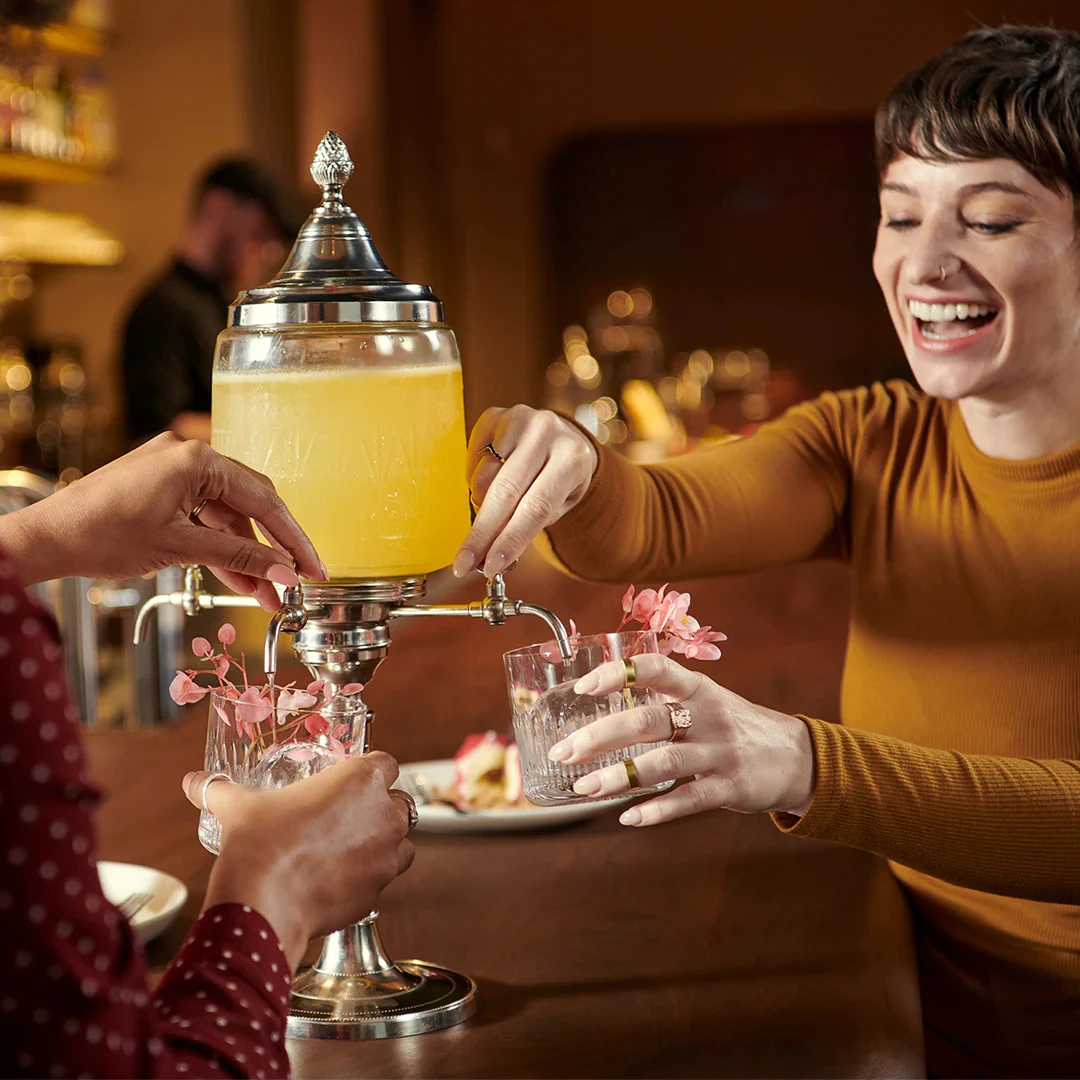 Photograph of guests sharing cocktails at a table.