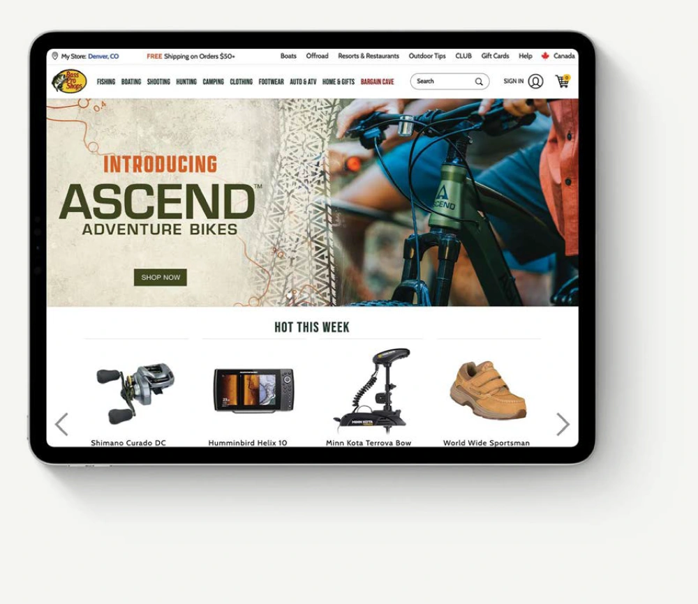 Bass Pro Shops website with Ascend bicycle creative on a tablet, presented against the matching neutral page background.